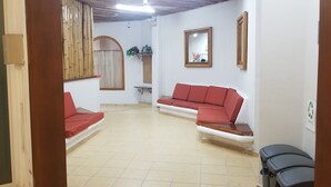 A room with two red sofas, a small table, a mirror, and a window with bamboo curtains. - Hotel Alux Cancun (Cancun)