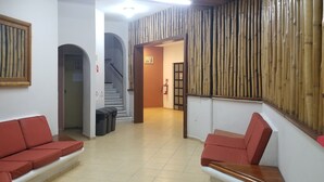 A reception area with red cushioned seating, a framed artwork, a staircase, and a bamboo wall. - Hotel Alux Cancun (Cancun)