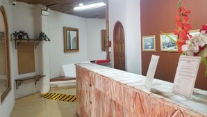 A reception area with a wooden reception desk, a bench, a mirror, and a wall-mounted sign. - Hotel Alux Cancun (Cancun)