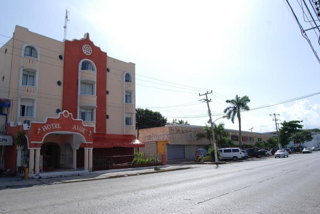 A hotel with a red facade, multiple balconies, and a clear sky.