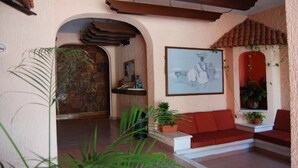 Um interior acolhedor com um sofá vermelho, um quadro e plantas em vasos.