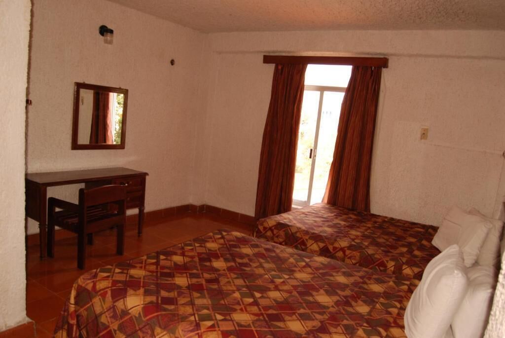 Una habitación con dos camas, un escritorio y una silla.