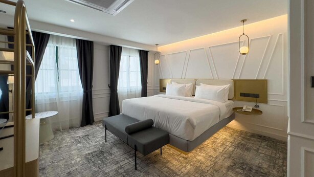 Een moderne hotelkamer met een groot bed, nachtkastjes, een bureau en een stoel.