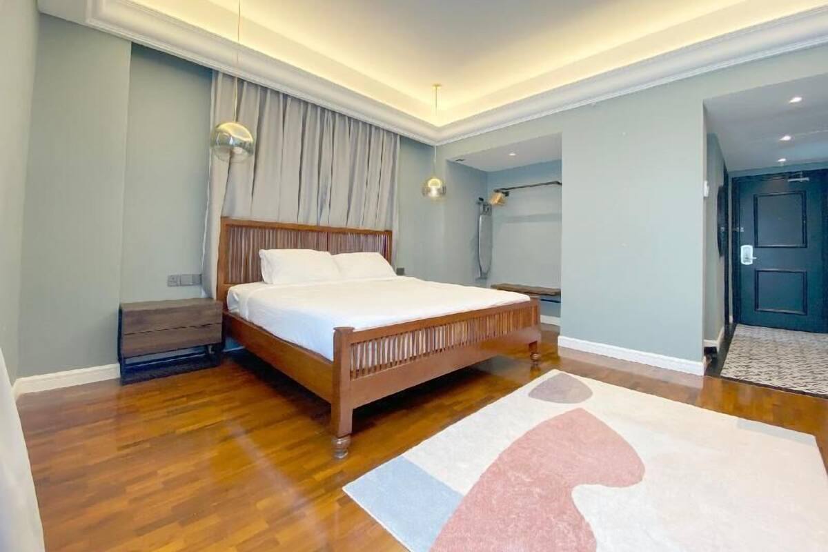 A modern bedroom with a wooden bed, a nightstand, a large window with curtains, and a ceiling light fixture.