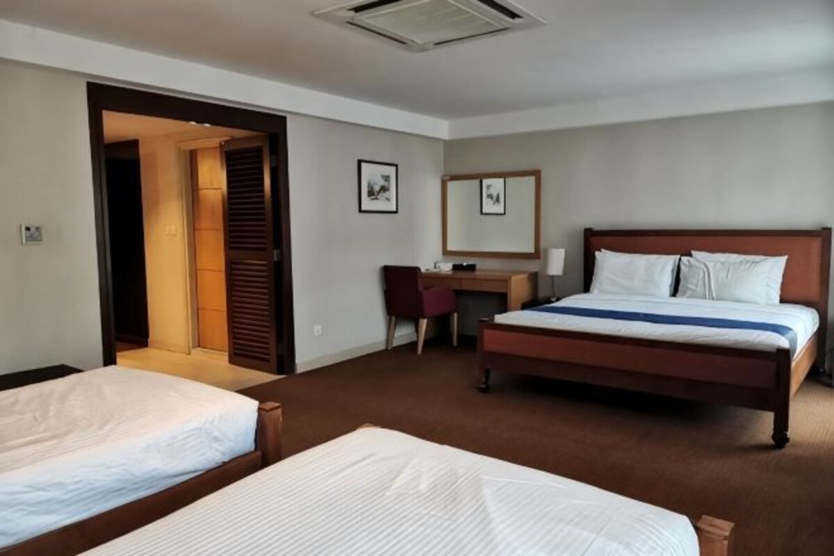 Habitación de hotel con dos camas, un escritorio, una silla y un espejo.