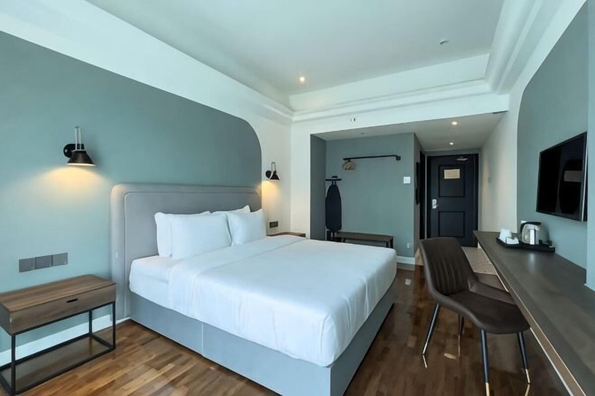 A modern hotel room with a large bed, a desk, and a TV.