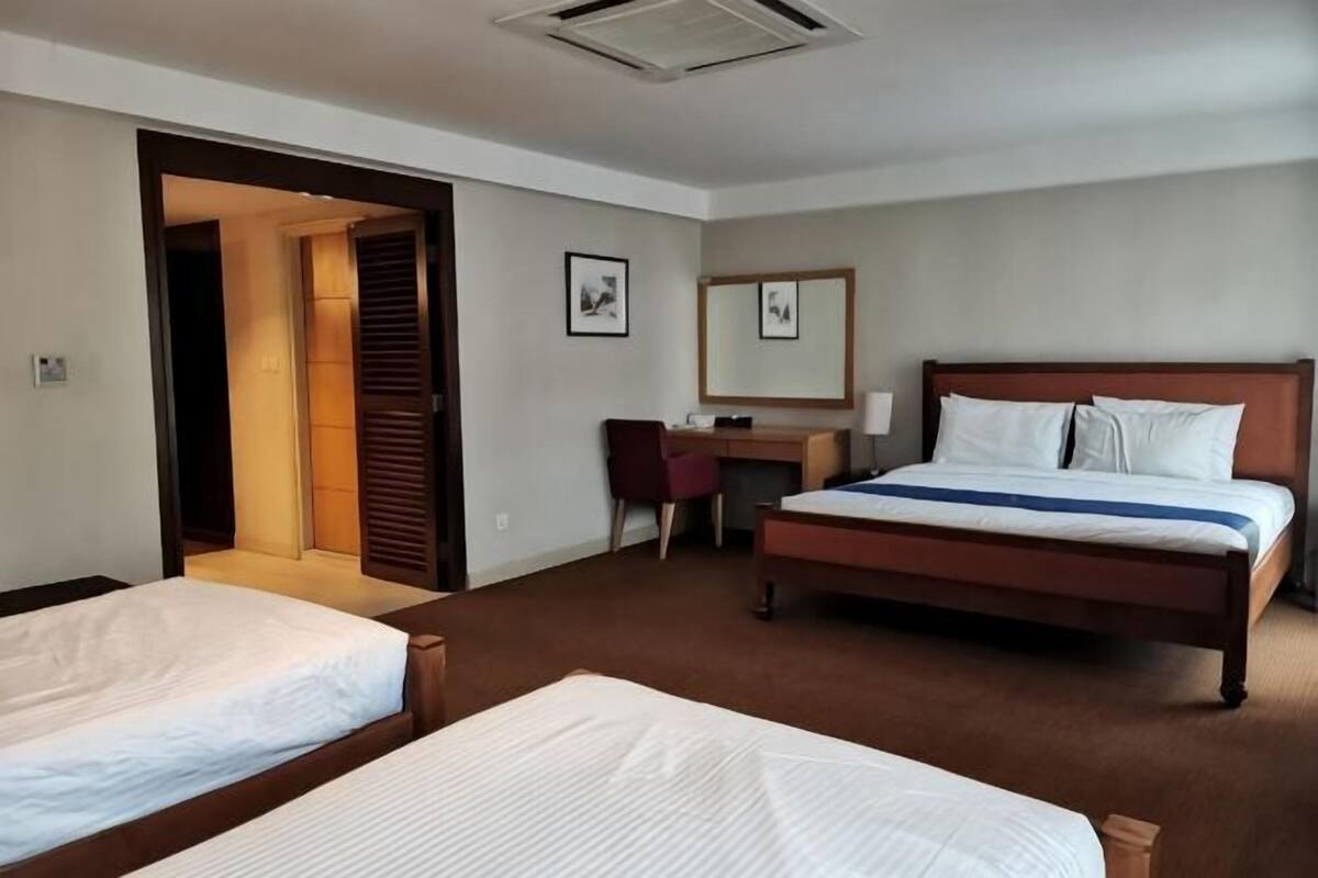 A hotel room with two beds, a desk, a chair, and a mirror.