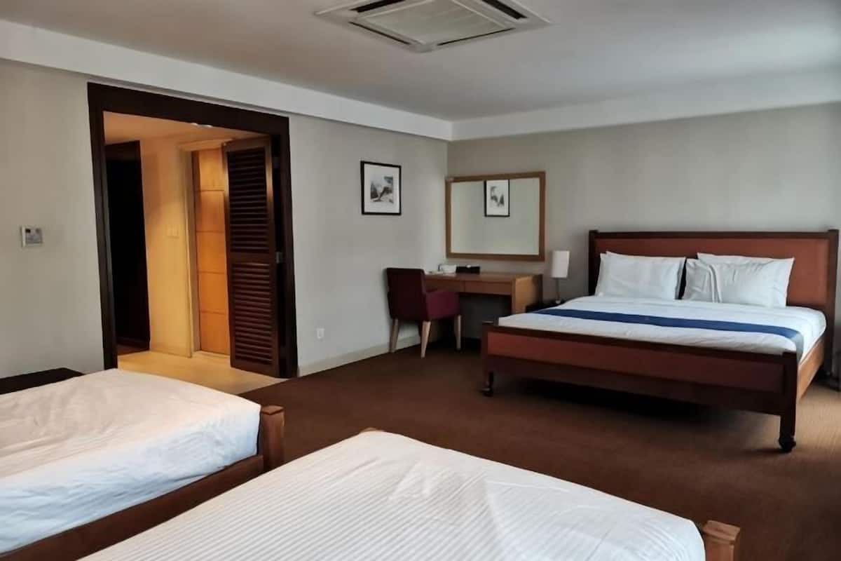 Quarto de hotel com duas camas, uma escrivaninha, uma cadeira e um espelho.