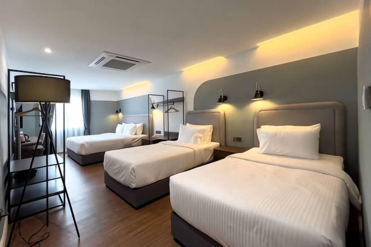 A hotel room with two beds, a desk, and a mirror.
