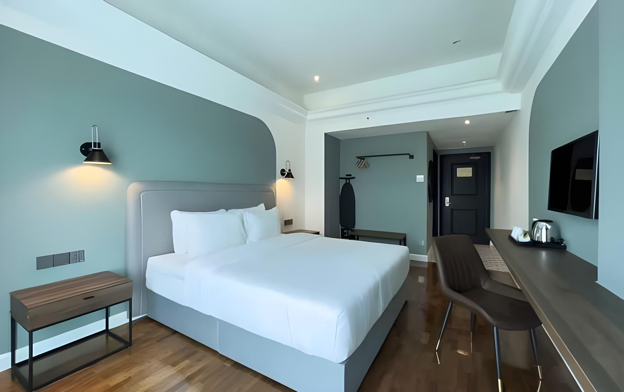 Una habitación de hotel moderna con una cama grande, mesitas de noche, un escritorio con silla y un televisor de pantalla plana.