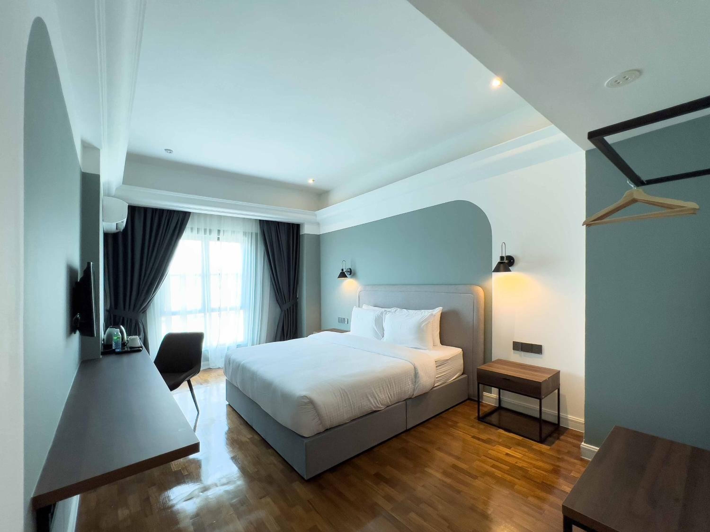 A modern hotel room with a large bed, bedside tables, a desk, and a chair.