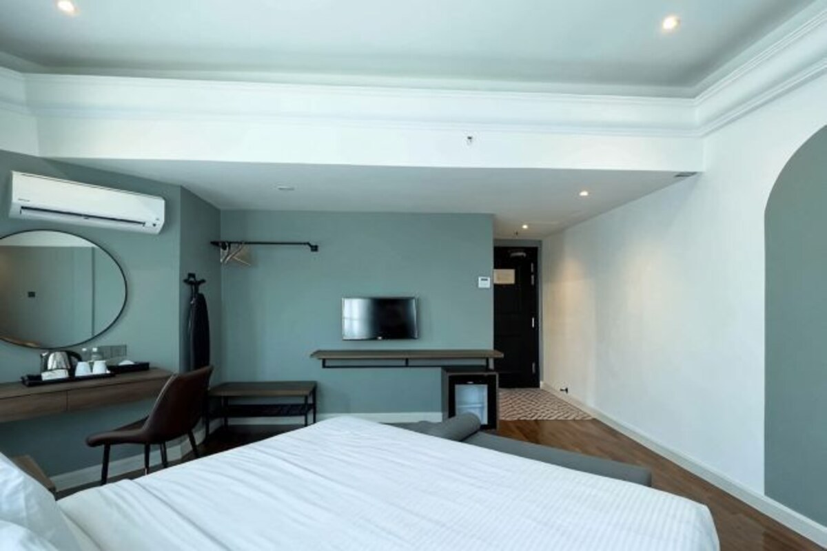 Una habitación de hotel moderna con cama, escritorio, silla, televisión y aire acondicionado.