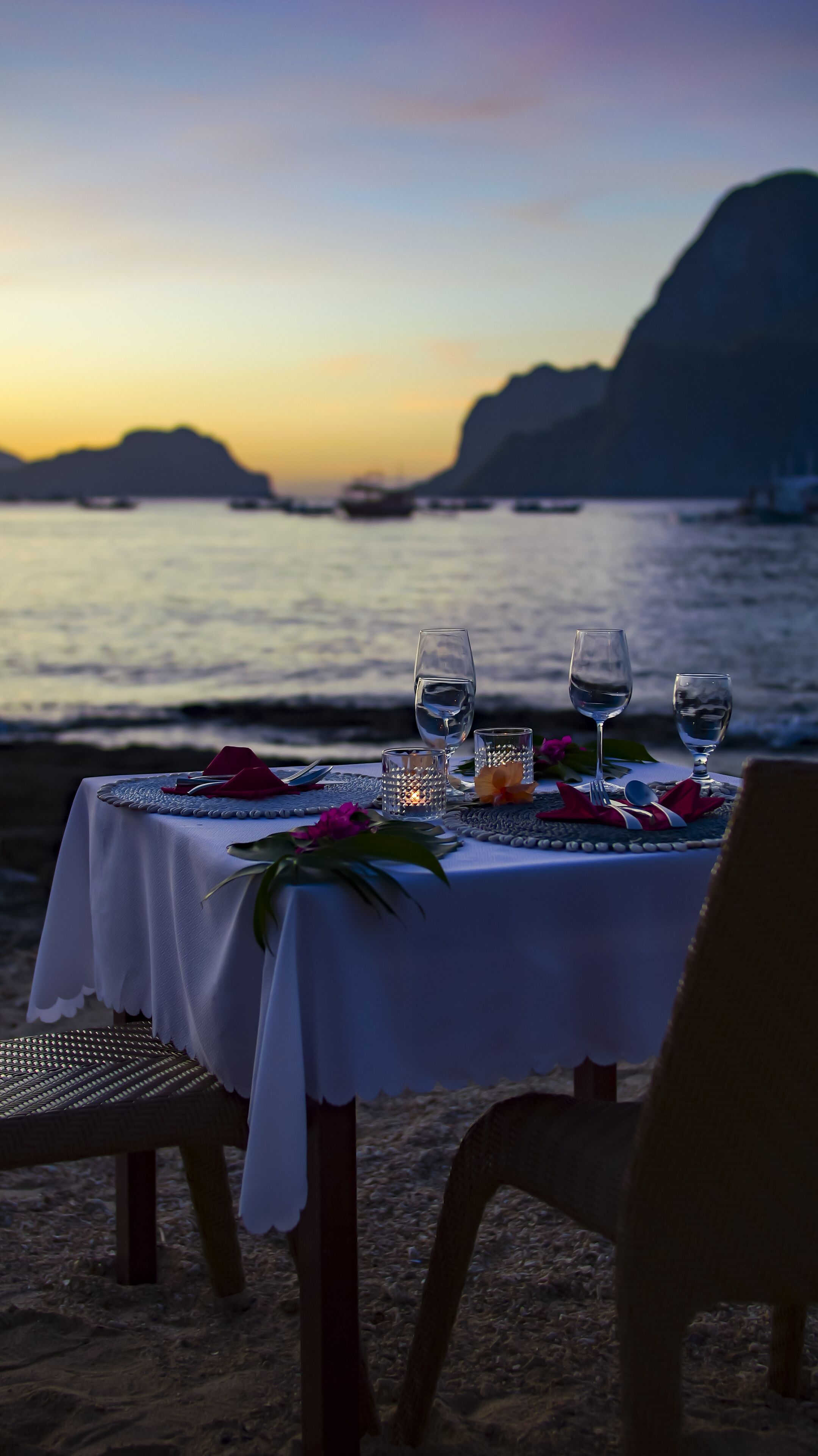 Mesa para dos con vista al mar y montañas al atardecer.