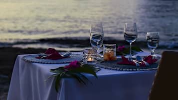 Mesa para dos con vista al mar y montañas al atardecer.