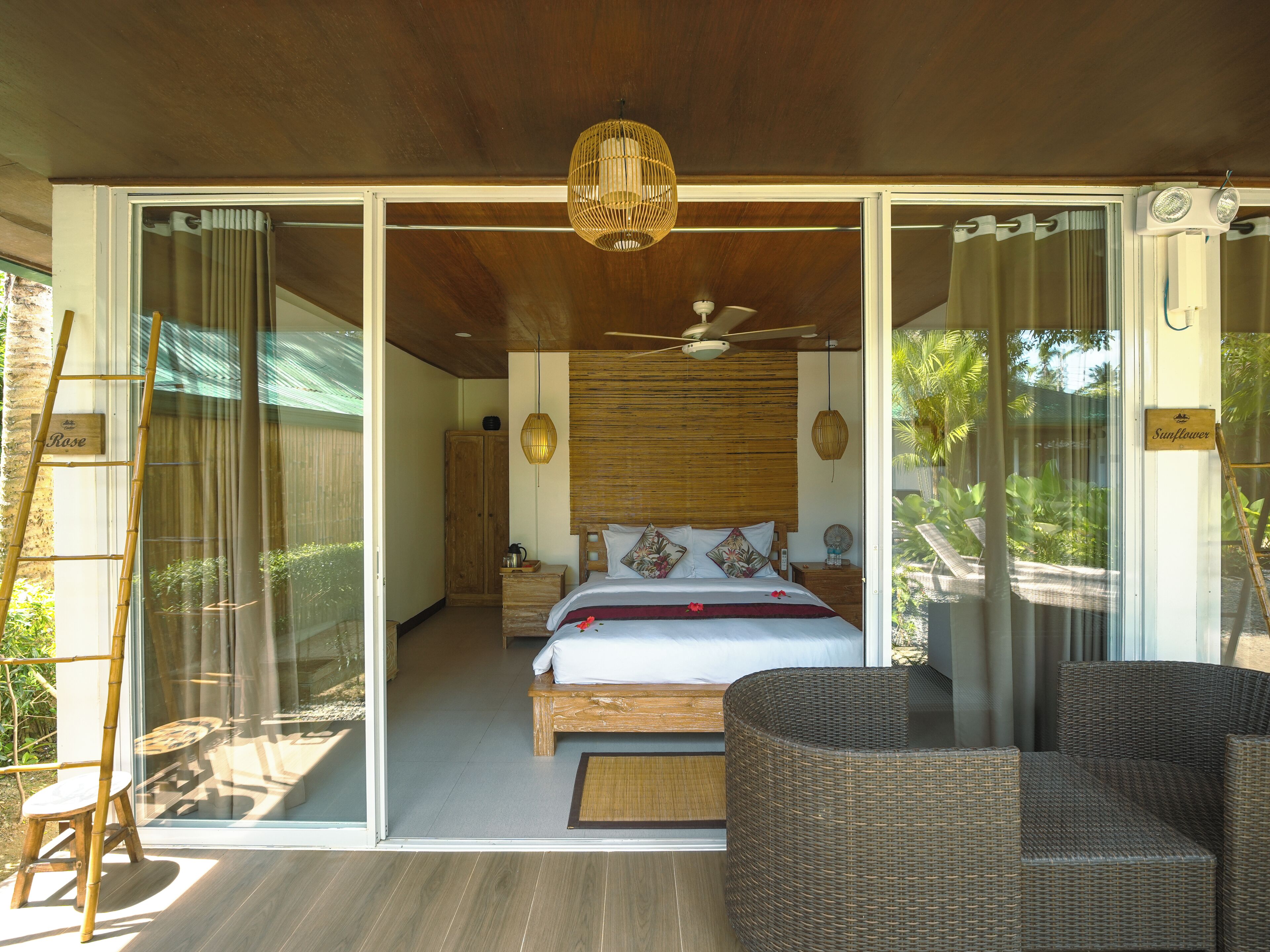 A bedroom with a bed, a ceiling fan, and a view of the outdoors.