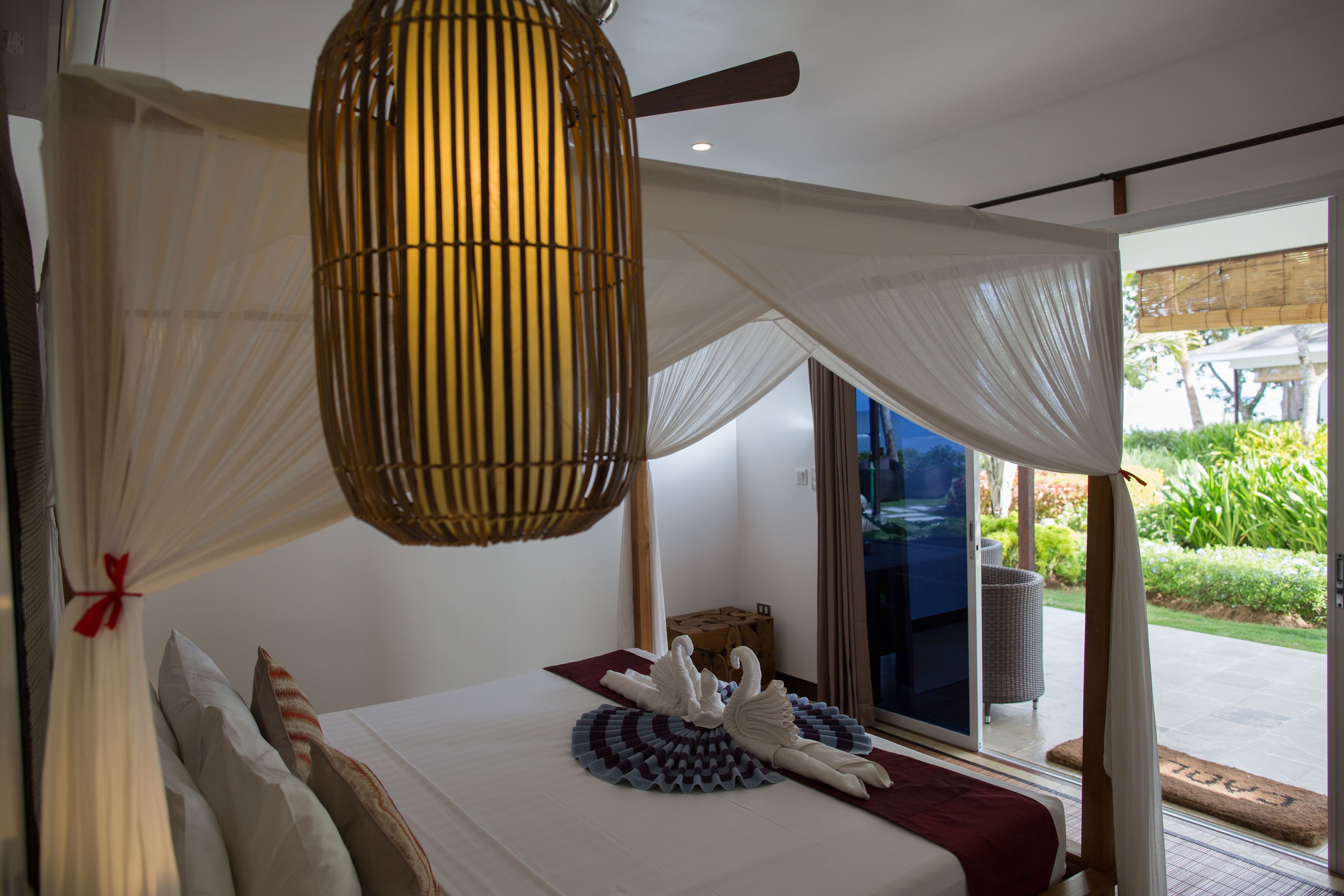 Quarto com cama de dossel, ventoinha no teto e vista para o exterior.