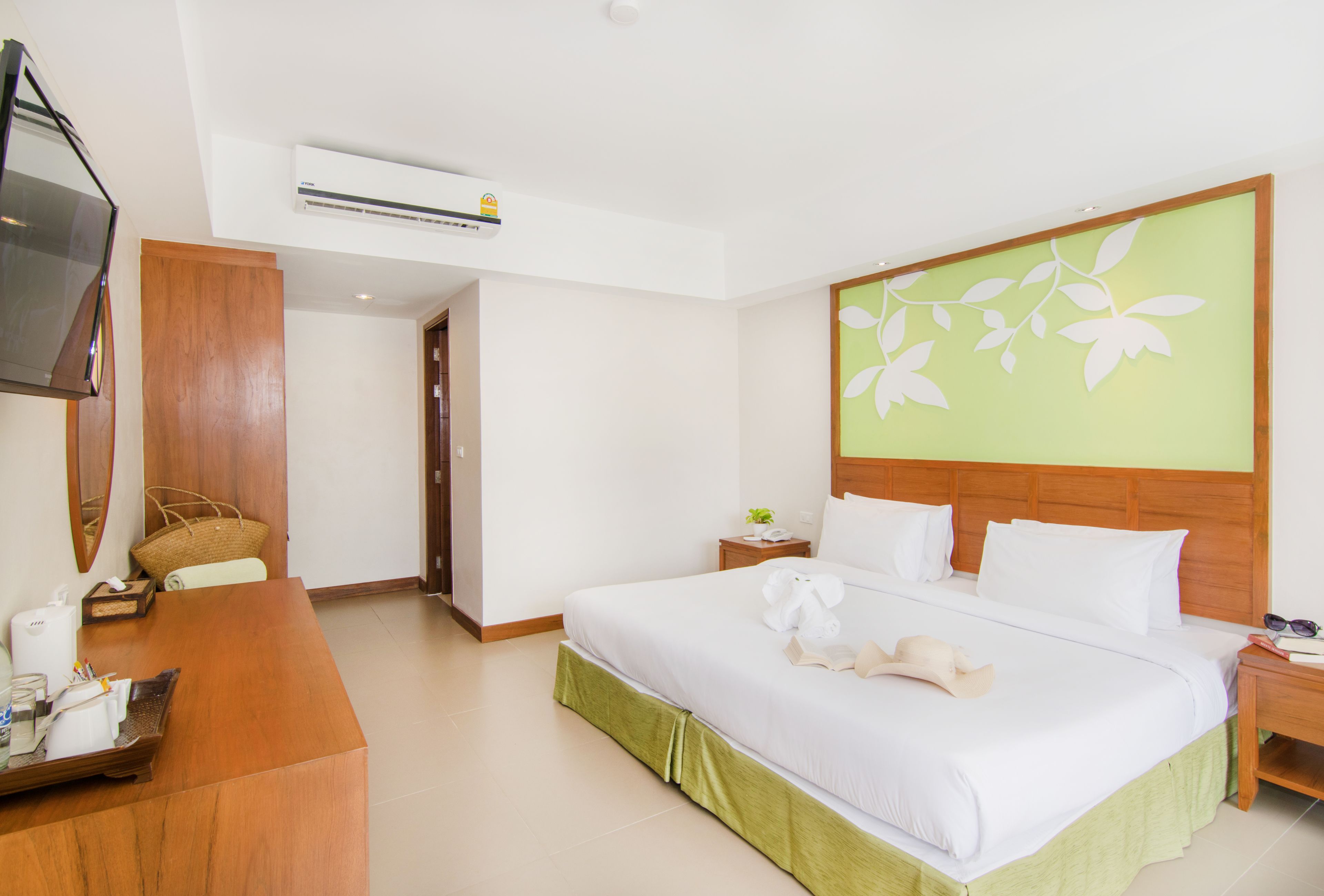 Una habitación de hotel con cama, escritorio, televisor y aire acondicionado.
