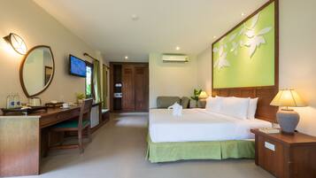 A hotel room with a bed, desk, chair, TV, and a wall-mounted air conditioner.
