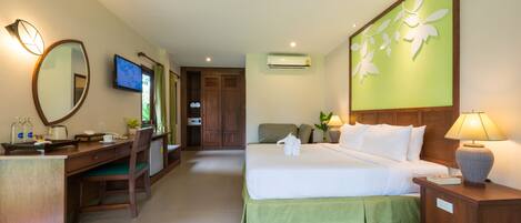 A hotel room with a bed, desk, chair, TV, and a wall-mounted air conditioner.