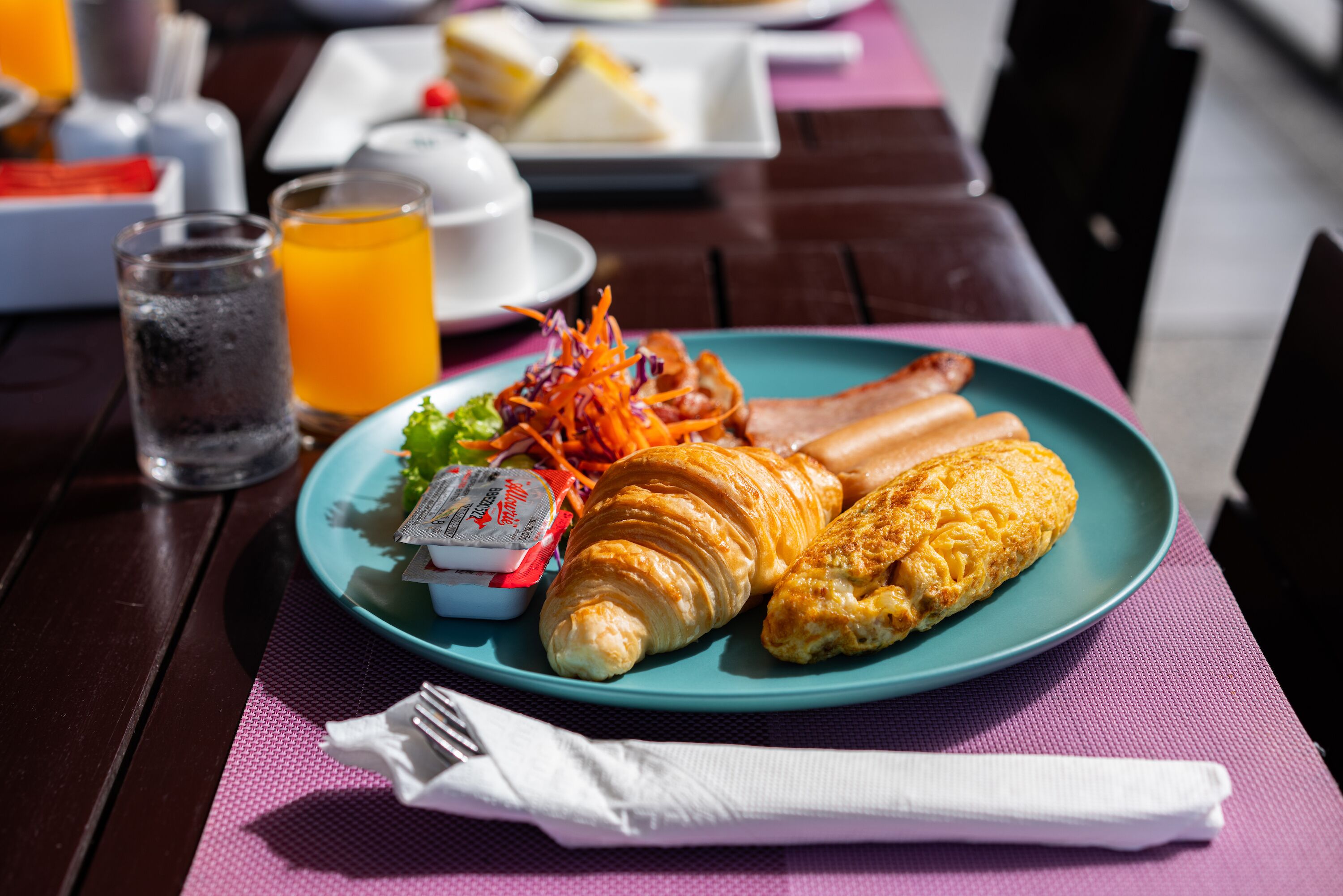 Um prato com croissants, uma salada e uma bebida sobre uma mesa.