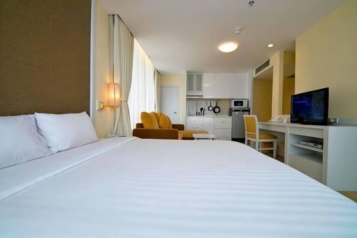 Une chambre d’hôtel équipée d’un lit, d’un bureau, d’une chaise, d’une télévision et d’une kitchenette.