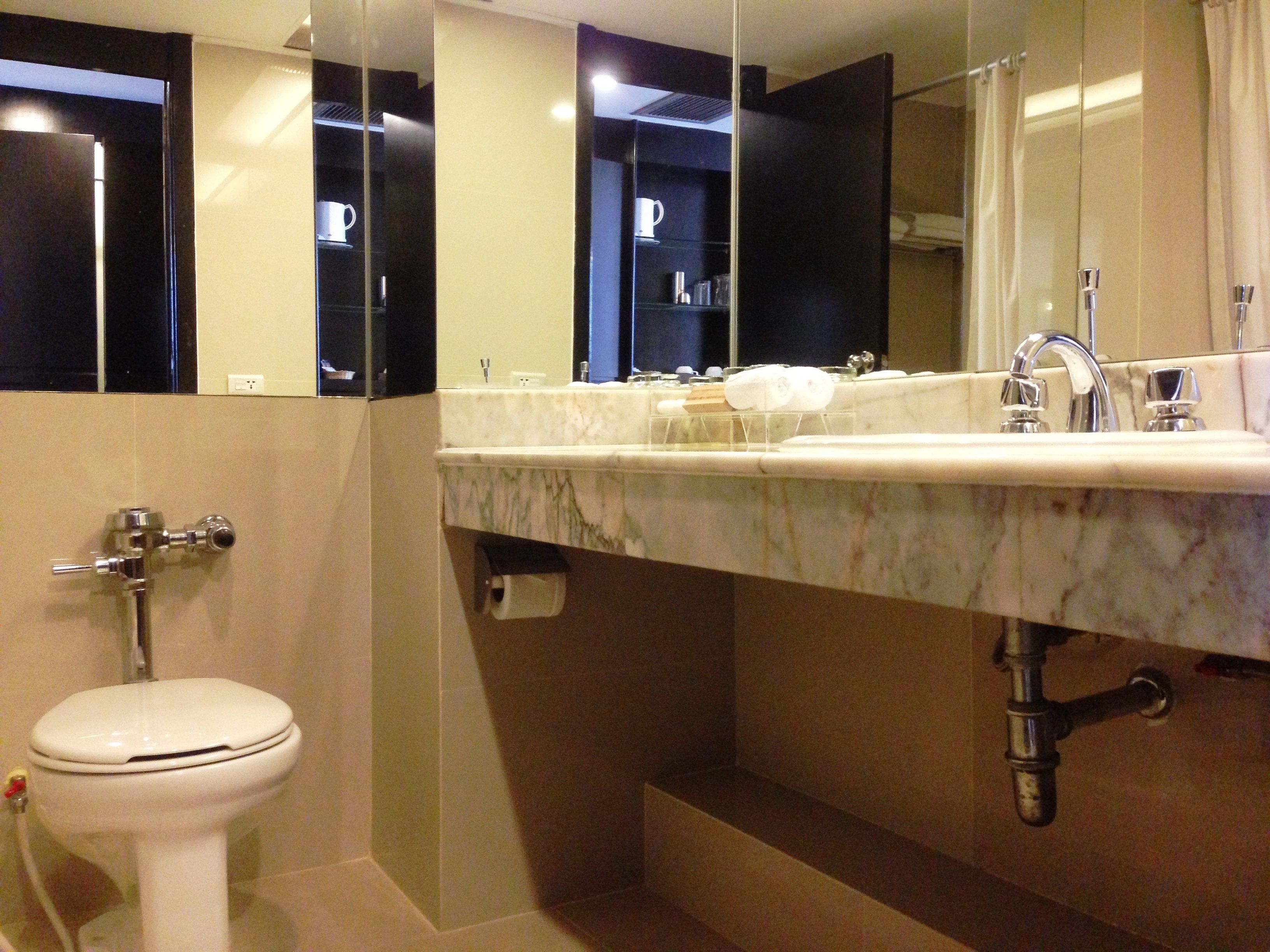 Un baño moderno con un lavabo de mármol, inodoro y un espejo grande.