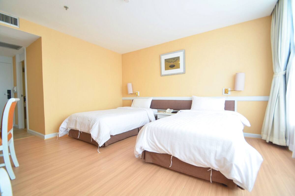 Une chambre d’hôtel avec deux lits, une table de chevet, une chaise et un tableau au mur.