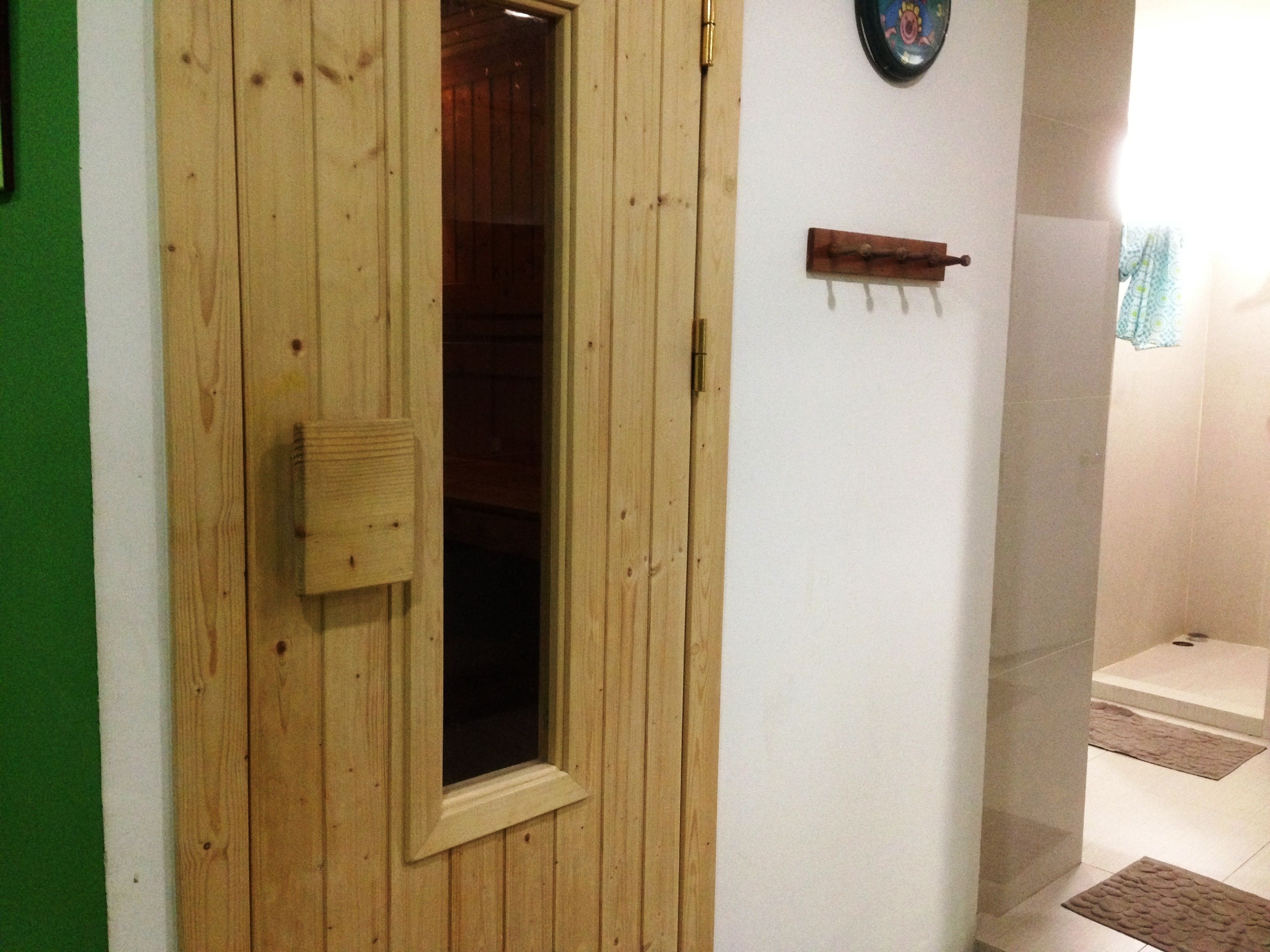 A wooden door with a window, a small wooden shelf with hooks, and a tiled floor.