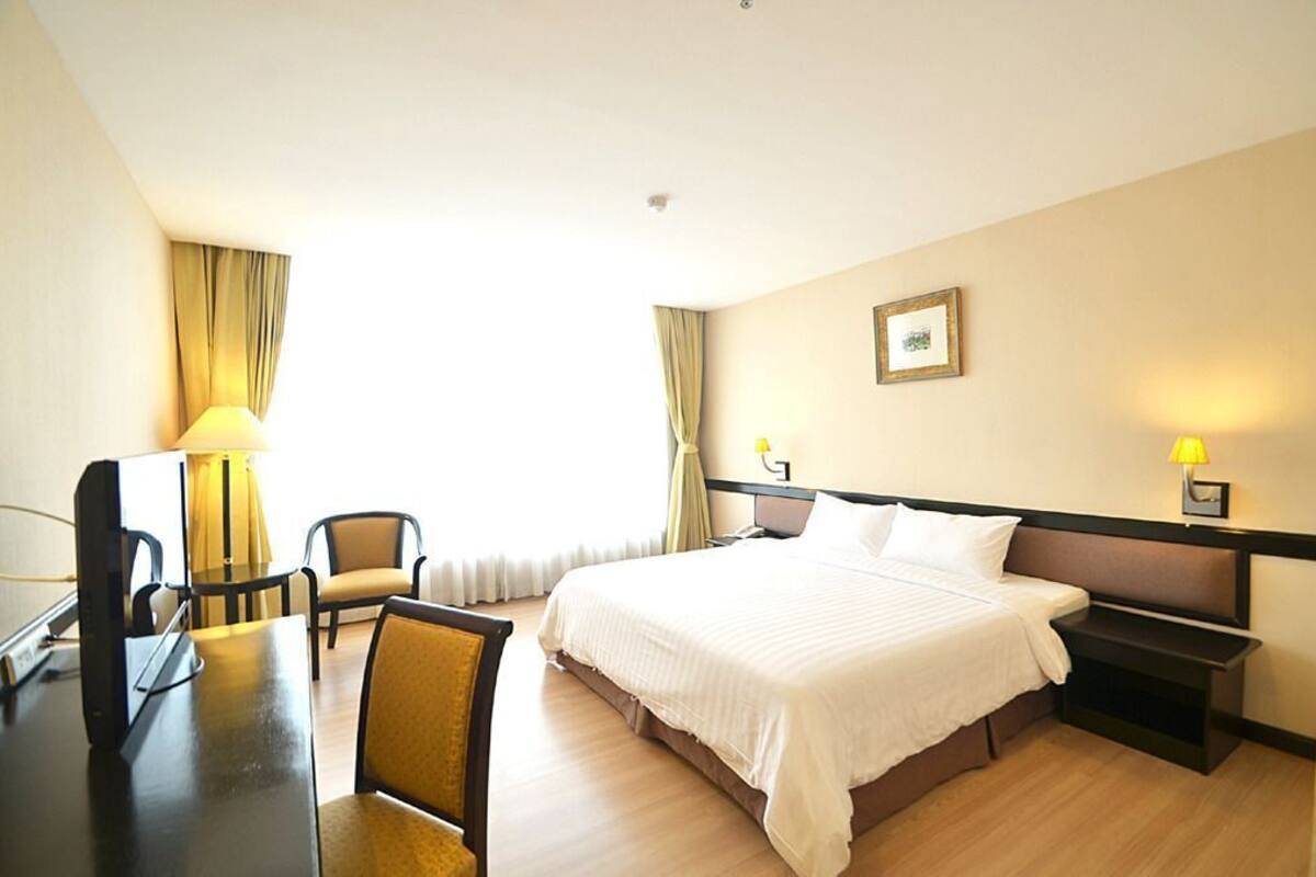 Une chambre d’hôtel comprenant un lit, des tables de chevet, un bureau avec une chaise et une lampe.