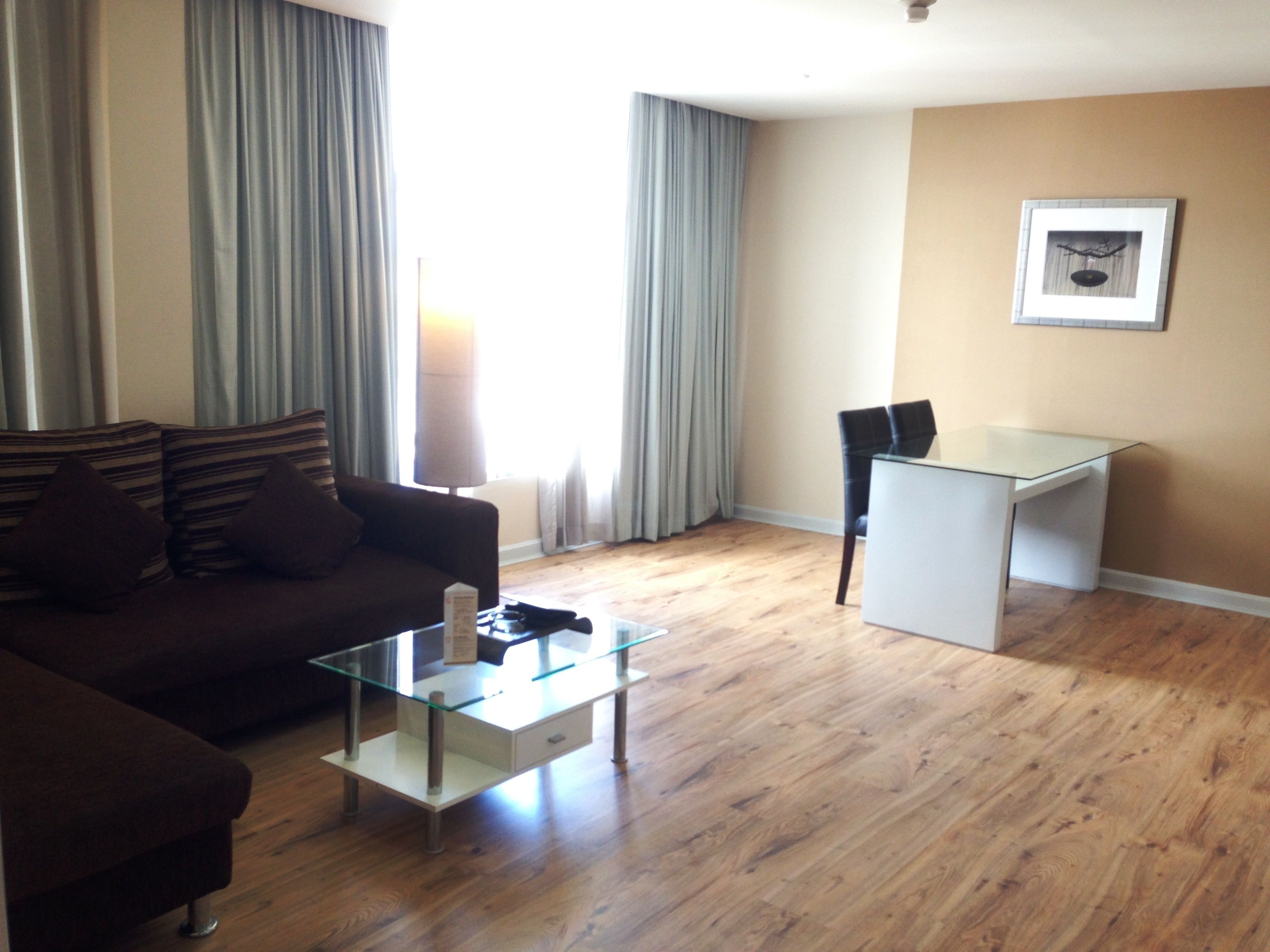 A living room with a sofa, a glass coffee table, a desk, and a chair.