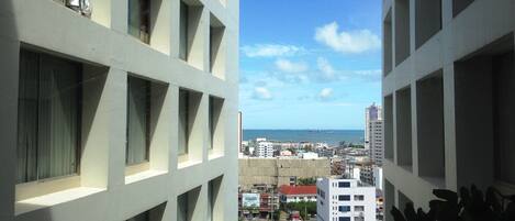 A view from a high-rise building overlooking a coastal cityscape with a clear sky.