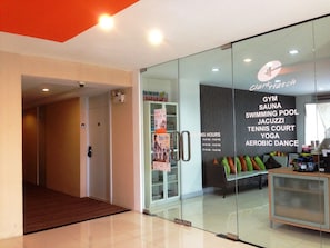 A modern fitness center with glass walls, a reception desk, and a variety of amenities including a gym, sauna, swimming pool, jacuzzi, tennis court, yoga, and aerobic dance classes. - The City Hotel Sriracha by BBH Japan (Si Racha)