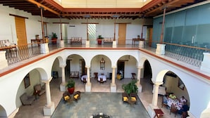 A spacious indoor courtyard with multiple arches, a covered upper level, and several seating areas. - Hotel Parador de Alcalá Oaxaca (Oaxaca)