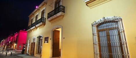 Una calle histórica con edificios amarillos, balcones decorados y un pavimento adoquinado.