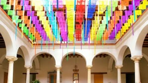 A spacious courtyard with arches and columns, featuring a colorful hanging decoration. - Hotel Parador de Alcalá Oaxaca (Oaxaca)