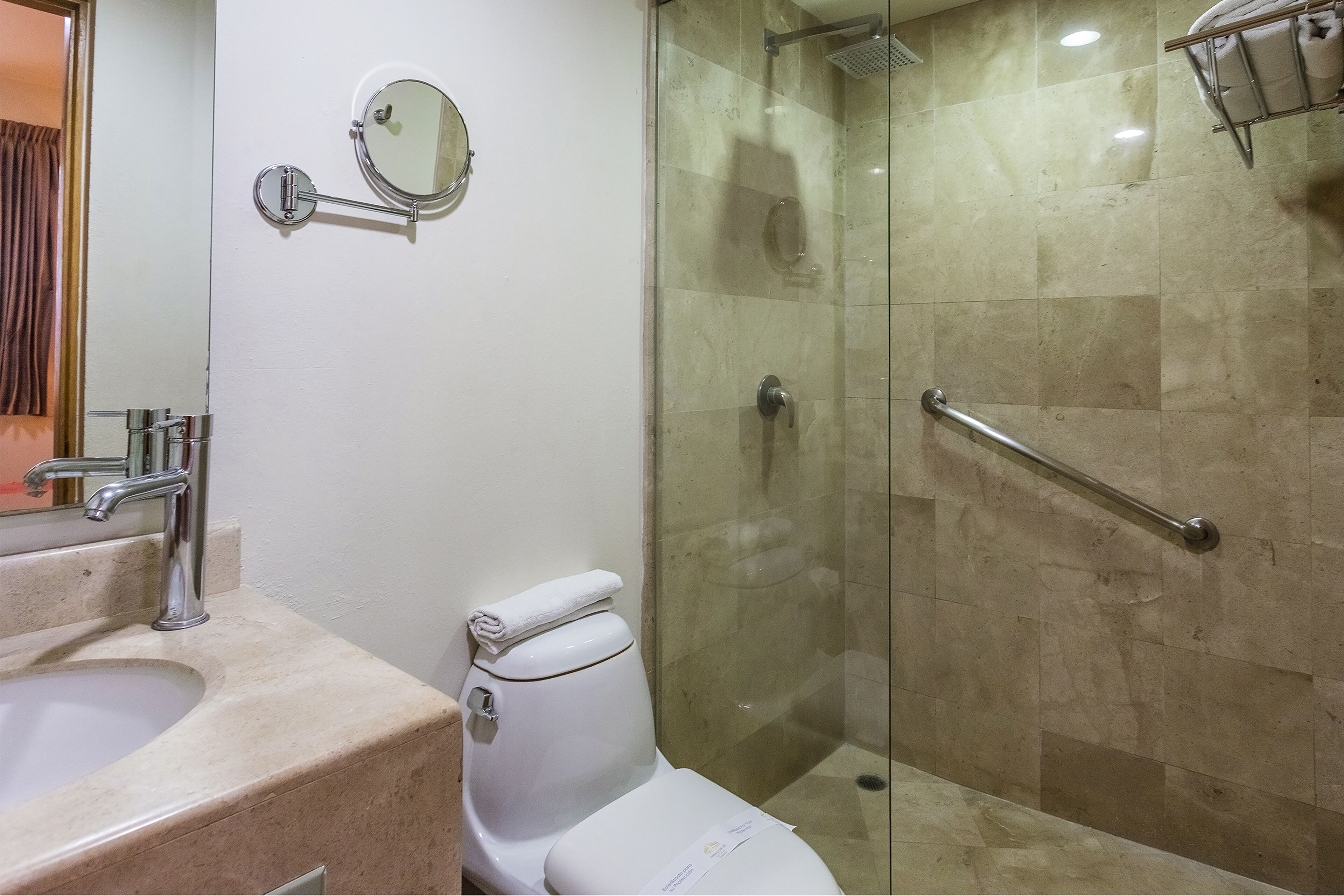 Een badkamer met een wastafel, toilet en een douchecabine met douchebeugel.