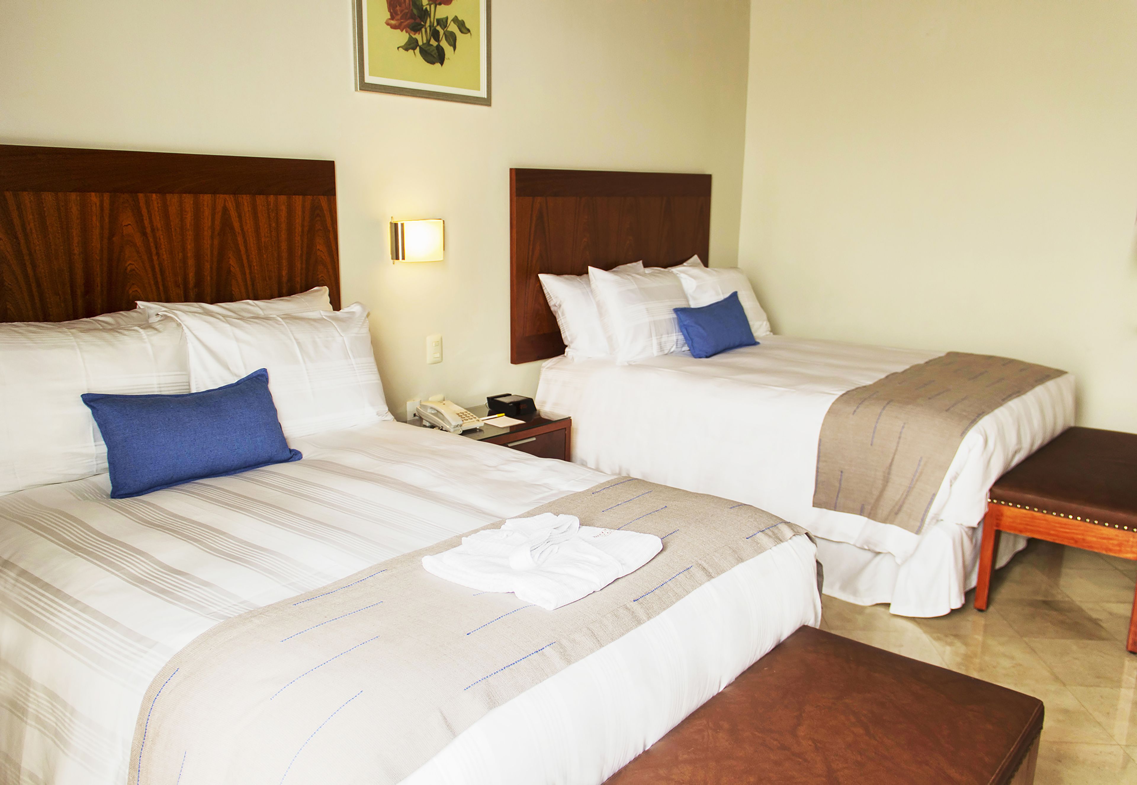 Two double beds with wooden headboards, white bedding, and blue pillows.