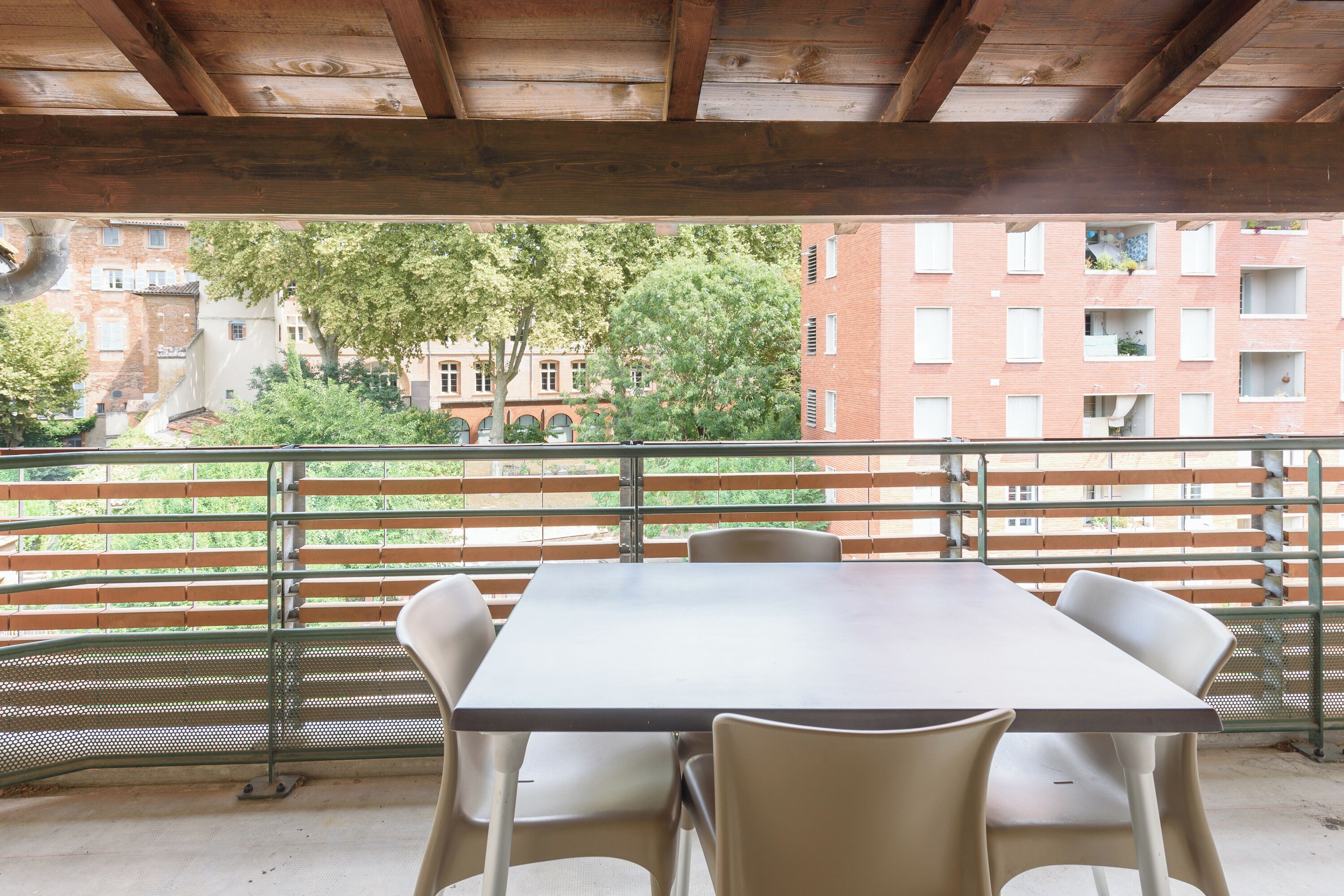 An outdoor patio with a table and chairs, overlooking a cityscape with buildings and trees.