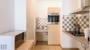 Una cocina compacta con microondas, horno y salpicadero a cuadros.