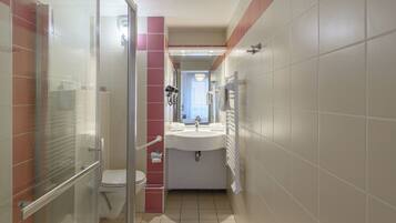 A bathroom with a glass shower enclosure, a toilet, a sink, and a mirror.