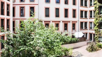 A multi-story building with a courtyard featuring a large tree and a covered seating area.