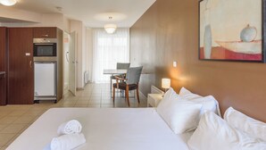 Una habitación de hotel con cama, escritorio, silla y kitchenette.