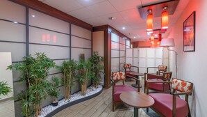 Una habitación con estética japonesa tradicional, que presenta suelo de tatami, mesas de madera bajas y sillas con cojines rojos.