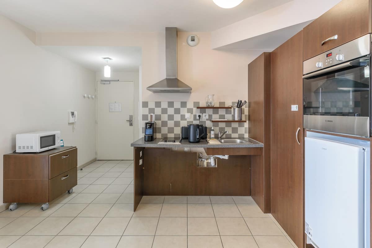 Una cocina compacta equipada con microondas, cafetera y refrigerador Bosch.