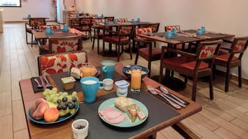 Un ambiente de desayuno con mesas, sillas y una variedad de alimentos y bebidas.