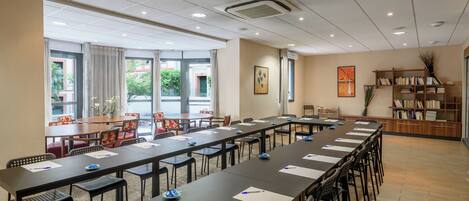 A conference room with a long table, multiple chairs, and a bookshelf.