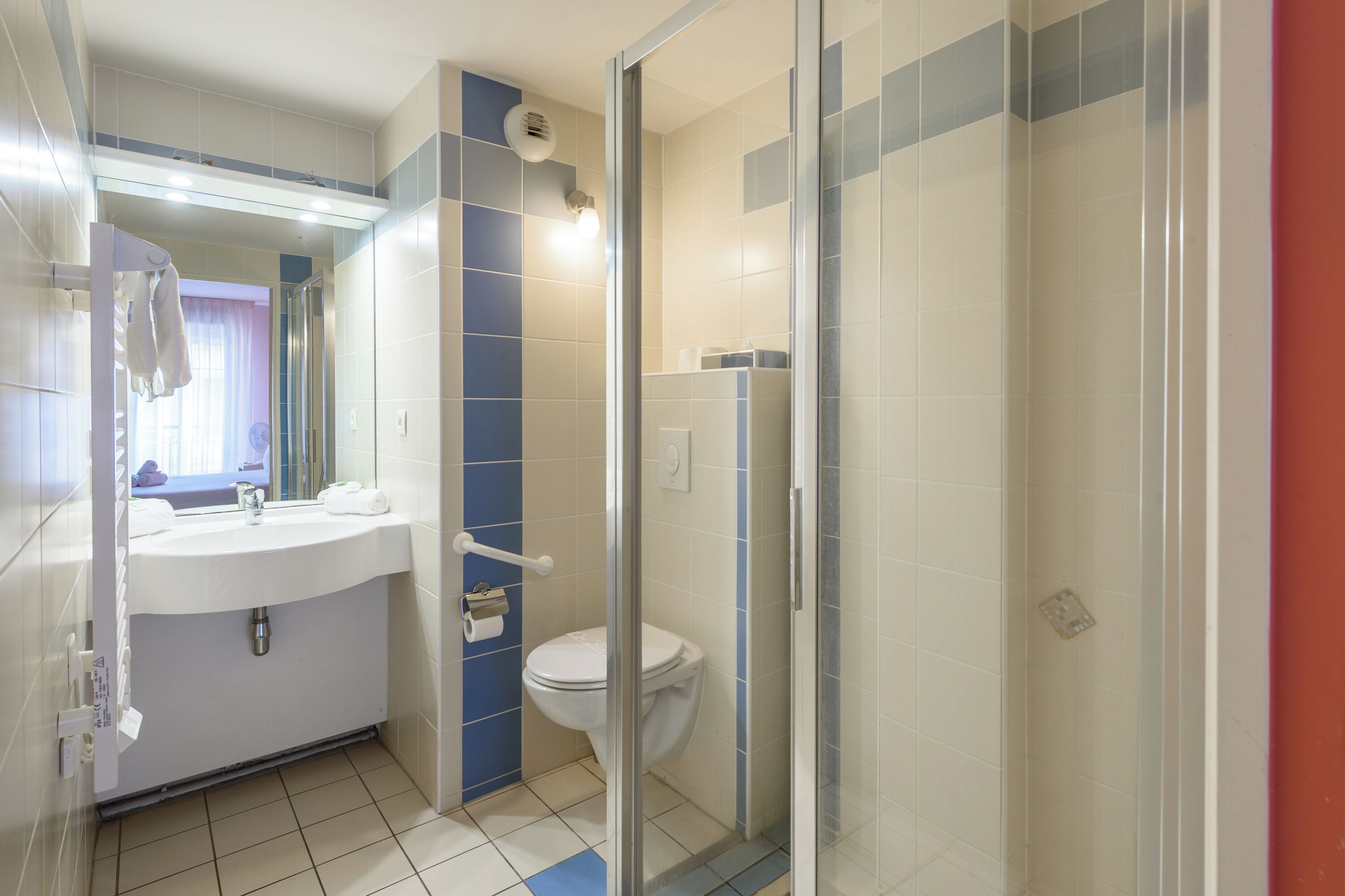 A bathroom with a sink, toilet, and glass shower enclosure.