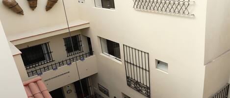 A multi-level courtyard with a tiled floor, a round table with chairs, and a small garden area.