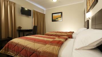 Een hotelkamer met een bed, een bureau, een stoel, een televisie en een schilderij aan de muur.