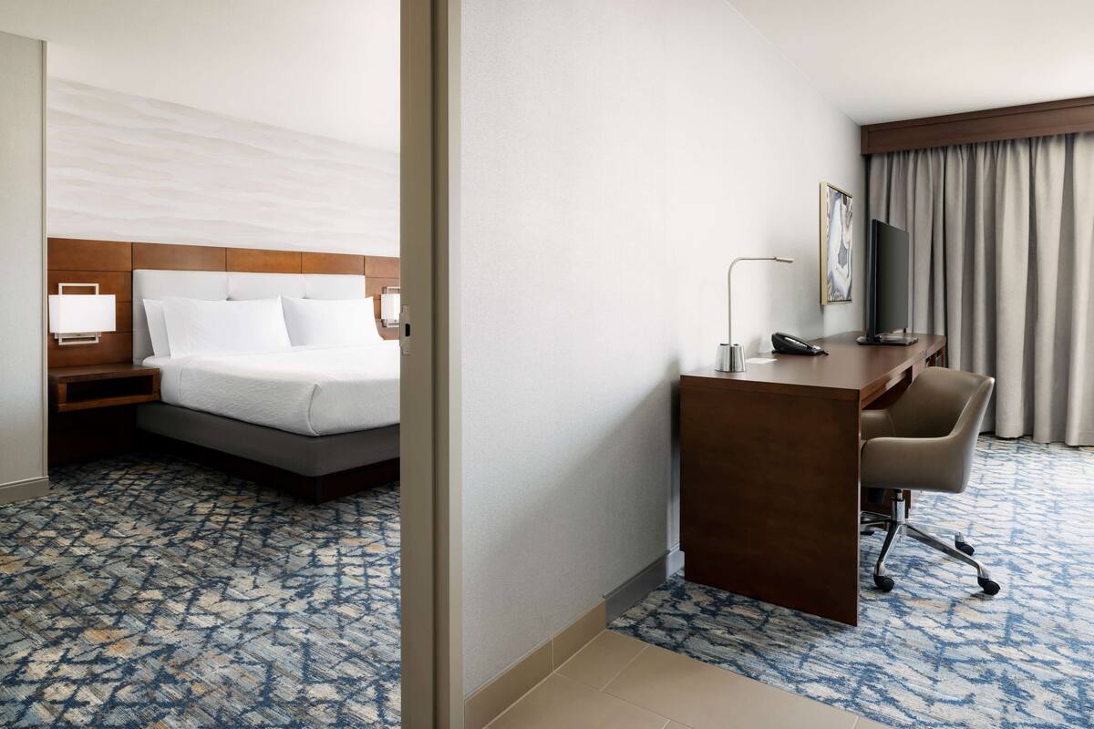 Een hotelkamer met een bed, bureau, stoel en televisie.